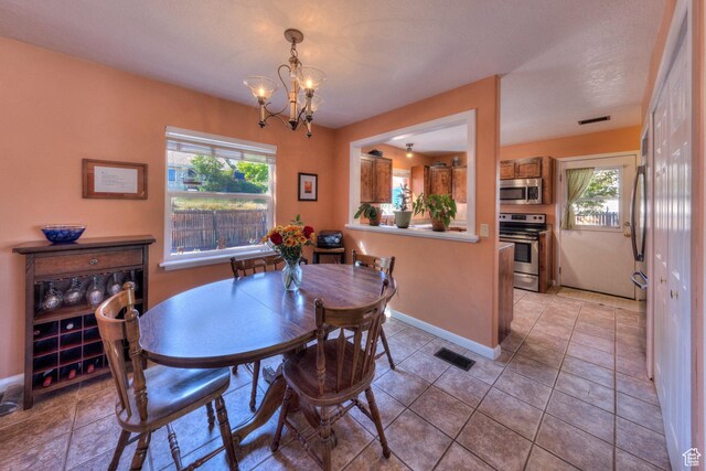 1122 E Holyoak Ln, Moab, UT 84532 - dining area featuring light tile patterned floors, visible vents, a healthy amount of sunlight, and an inviting chandelier