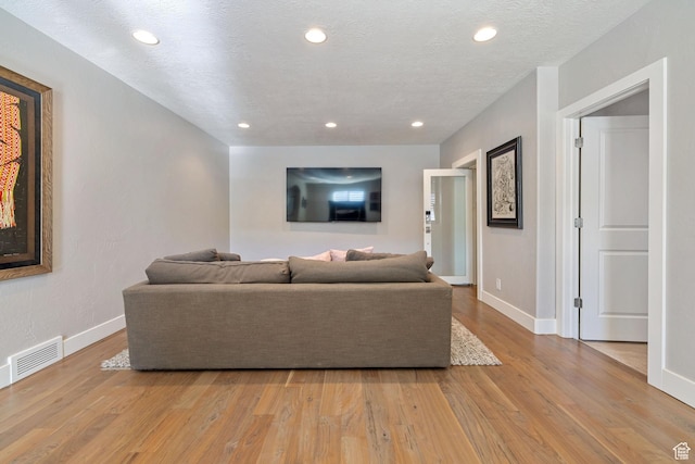living area with visible vents, baseboards, recessed lighting, and light wood-style floors