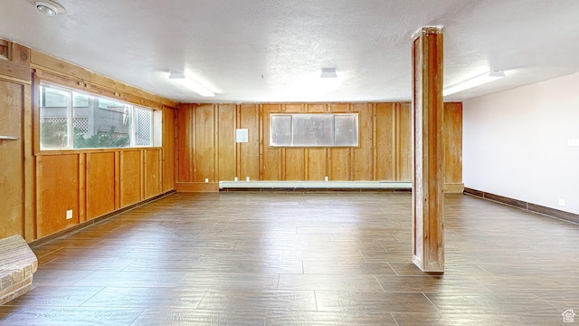 410 S Woodland Hills Dr, Woodland Hills, UT 84653 - unfurnished room featuring dark wood-style flooring, baseboards, a textured ceiling, wooden walls, and a baseboard radiator