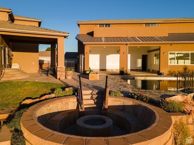 rear view of property with metal roof, fence, a patio, a standing seam roof, and stucco siding