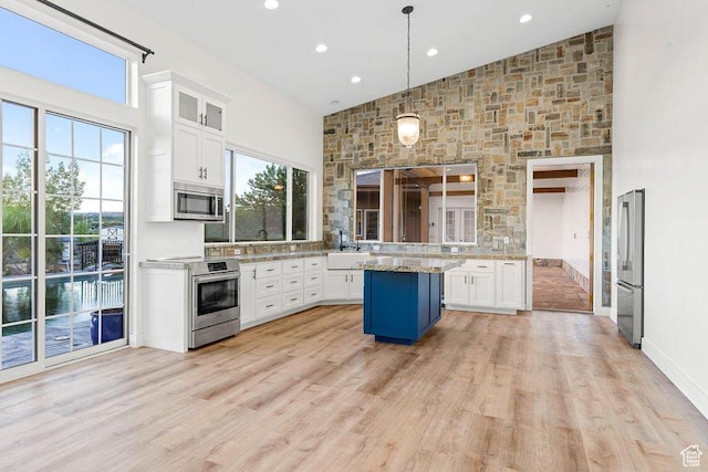 kitchen featuring a healthy amount of sunlight, white cabinetry, high vaulted ceiling, and stainless steel appliances