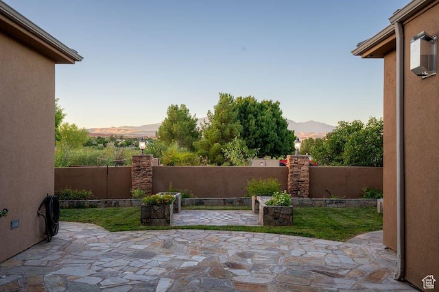patio terrace at dusk featuring a mountain view and fence