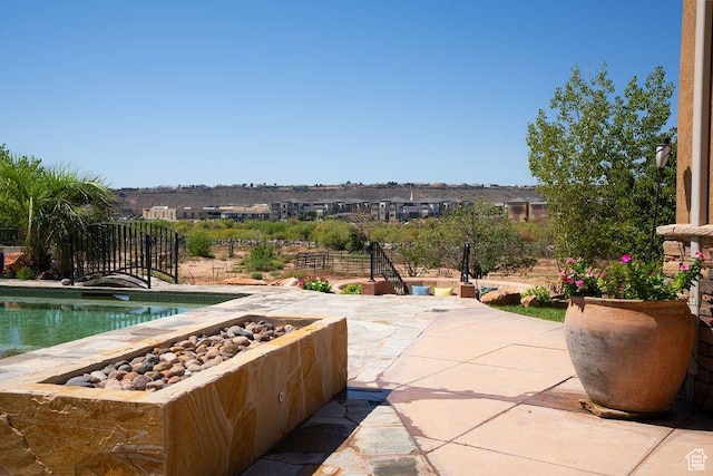 view of patio featuring a fire pit, fence, and an outdoor pool