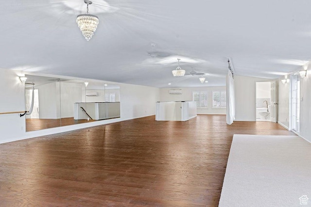 unfurnished living room featuring baseboards, a notable chandelier, wood finished floors, and lofted ceiling
