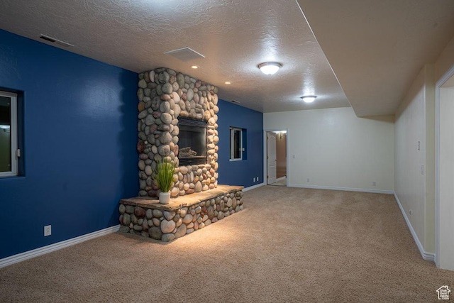 unfurnished living room with carpet flooring, a textured ceiling, baseboards, and visible vents
