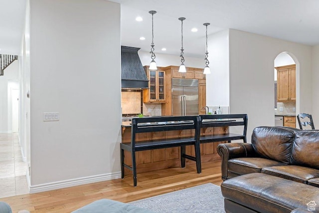 living room with baseboards, light wood-type flooring, arched walkways, and recessed lighting