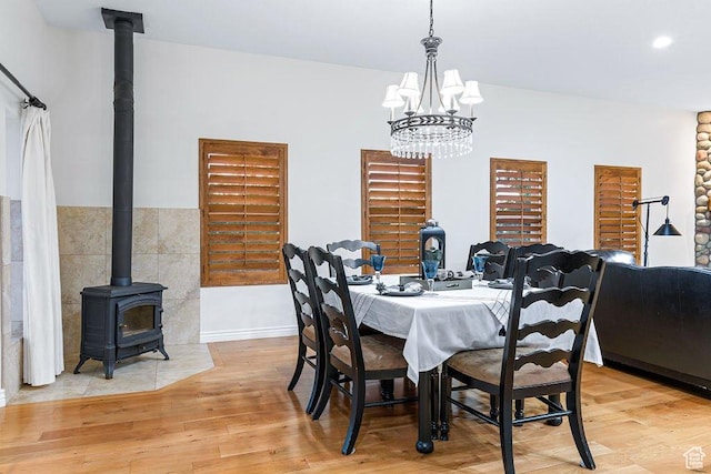 dining area featuring light wood-style floors, a wood stove, and an inviting chandelier