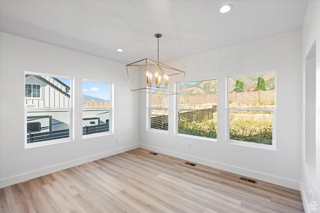 unfurnished dining area featuring light wood finished floors, baseboards, recessed lighting, and an inviting chandelier