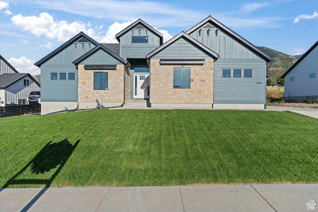 view of front of house with stone siding, board and batten siding, and a front yard