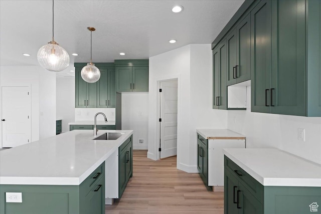 kitchen with light wood-style flooring, a sink, green cabinetry, and recessed lighting