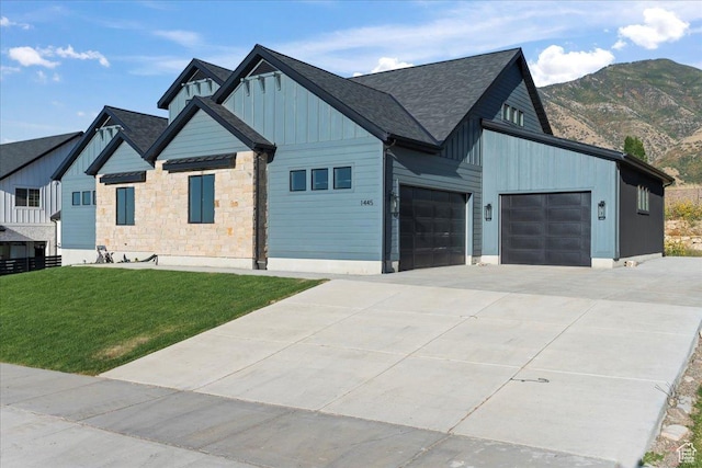 view of front of property with stone siding, a garage, a front lawn, board and batten siding, and driveway