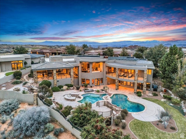 2196 W Long Sky Dr, St George, UT 84770 - back of property at dusk with a fenced backyard, stucco siding, a patio, and a balcony