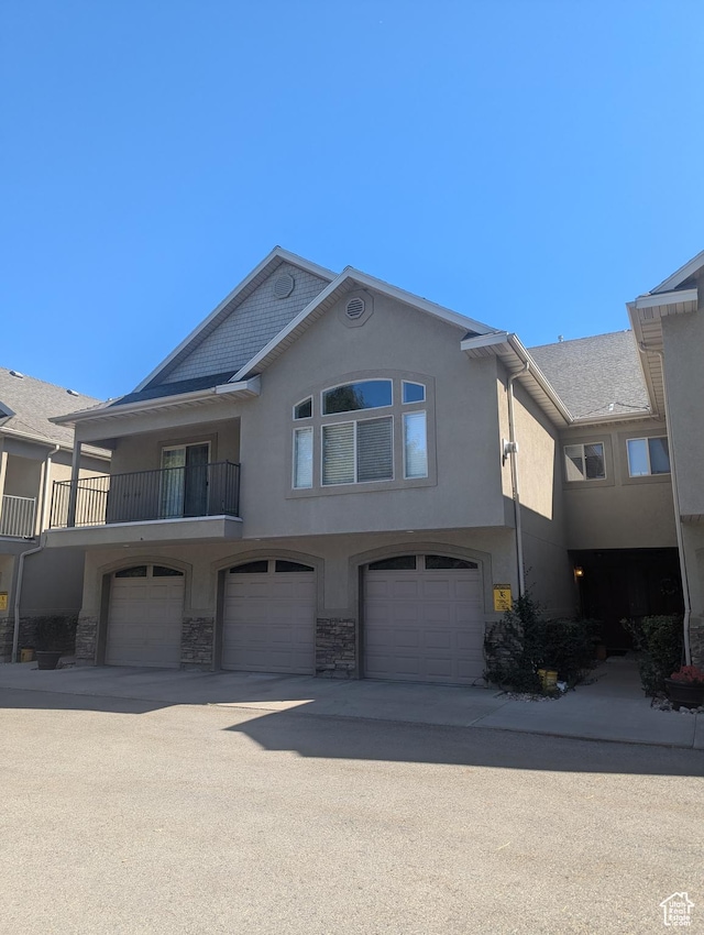 townhome / multi-family property with stone siding, stucco siding, driveway, and a garage