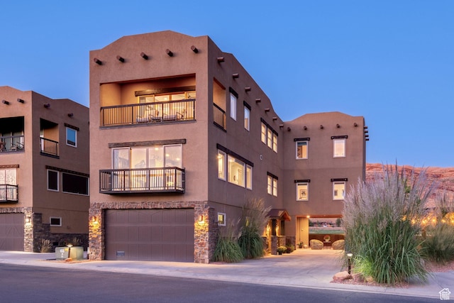 1261 N Main Rubicon Trl Unit M-14, Moab, UT 84532 - view of front facade featuring stucco siding, an attached garage, stone siding, and a balcony