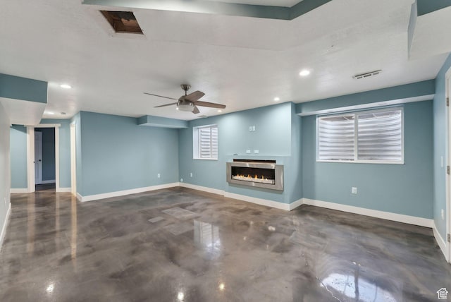 unfurnished living room featuring recessed lighting, ceiling fan, finished concrete flooring, baseboards, and a glass covered fireplace