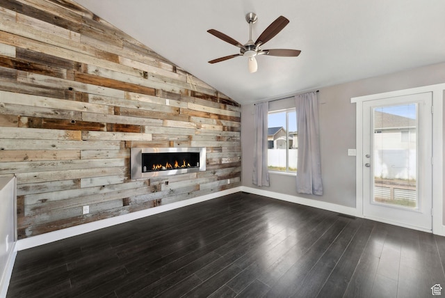 unfurnished living room with a fireplace, ceiling fan, wooden walls, vaulted ceiling, and dark wood-style floors