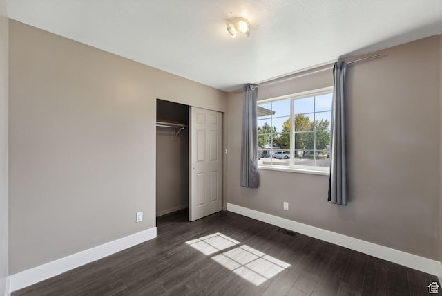 unfurnished bedroom with baseboards, visible vents, and dark wood-type flooring