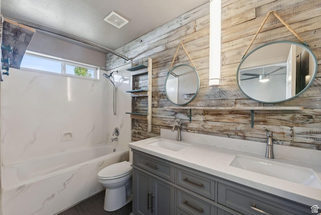 full bathroom featuring toilet, visible vents, wood walls, and a sink
