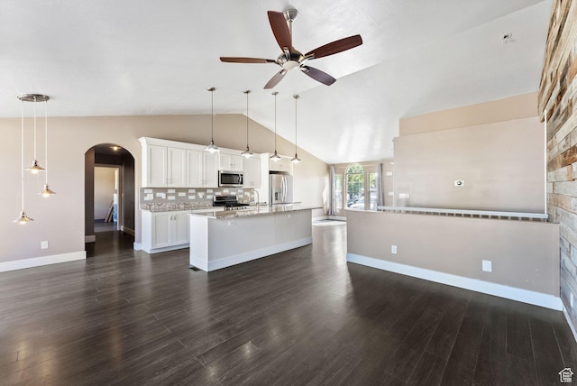kitchen featuring stainless steel appliances, open floor plan, lofted ceiling, and arched walkways