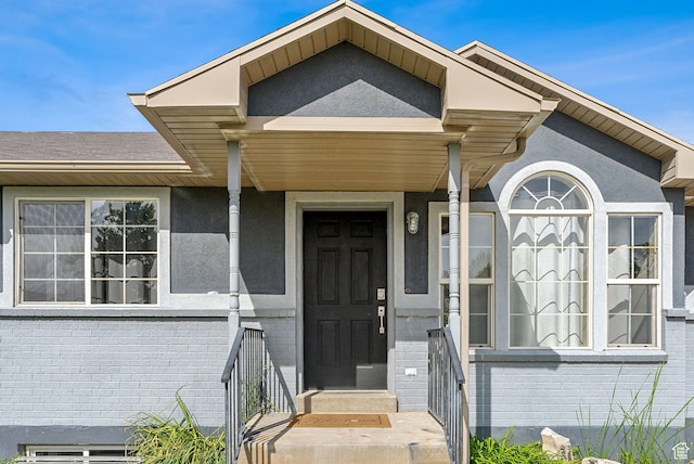 view of exterior entry featuring stucco siding and brick siding