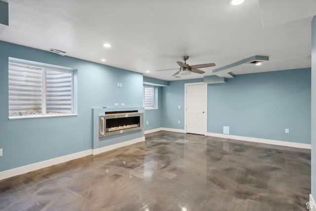 unfurnished living room with a ceiling fan, visible vents, baseboards, a warm lit fireplace, and recessed lighting