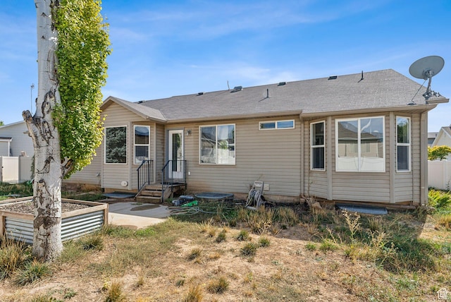 rear view of property featuring roof with shingles and fence
