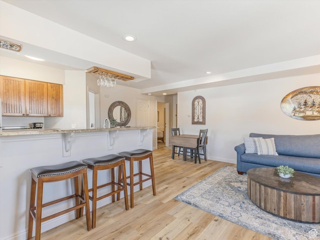 424 Park Ave Unit D, Park City, UT 84060 - kitchen featuring a kitchen bar, light wood-type flooring, baseboards, recessed lighting, and light stone countertops