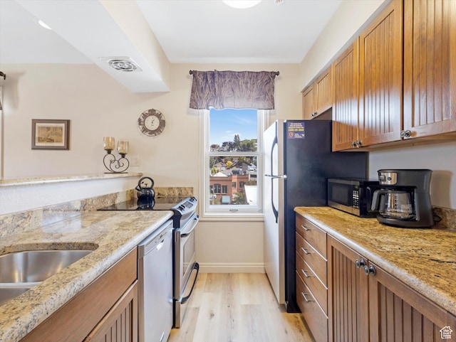 424 Park Ave Unit D, Park City, UT 84060 - kitchen featuring appliances with stainless steel finishes, light wood finished floors, brown cabinetry, and baseboards