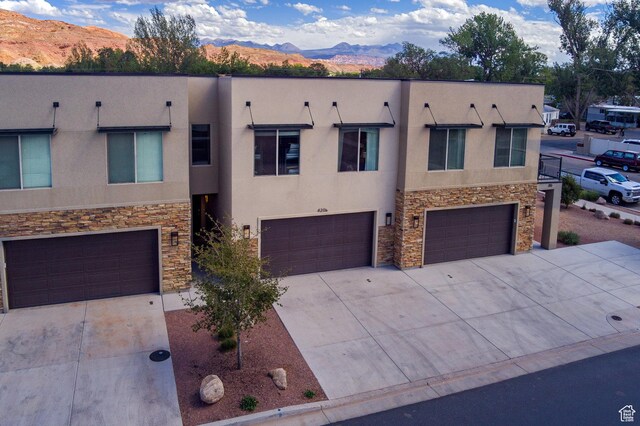 420 N 600 W, Moab, UT 84532 - view of front facade with stone siding, a mountain view, an attached garage, stucco siding, and concrete driveway