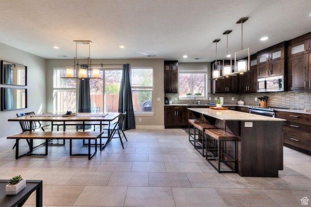 420 N 600 W, Moab, UT 84532 - kitchen featuring stainless steel appliances, a kitchen island, dark brown cabinets, glass insert cabinets, and a breakfast bar