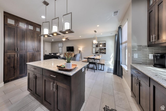 420 N 600 W, Moab, UT 84532 - kitchen with decorative backsplash, dark brown cabinets, a center island, glass insert cabinets, and light stone counters