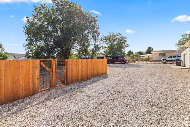 view of yard with a gate, driveway, and fence