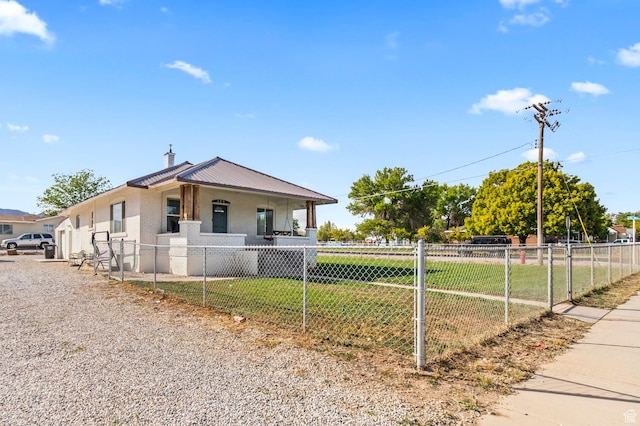 bungalow-style home with a front yard, a fenced front yard, and metal roof