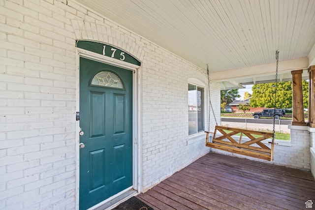 doorway to property featuring brick siding and a porch