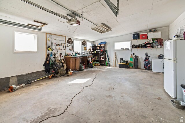 garage featuring a workshop area, a garage door opener, and freestanding refrigerator