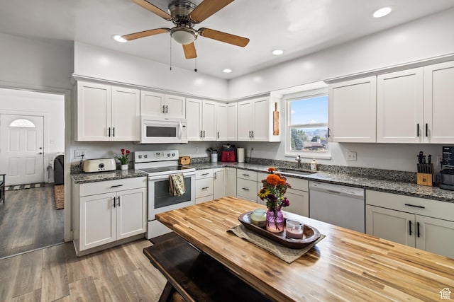 kitchen with a sink, a ceiling fan, wooden counters, light wood-type flooring, and white appliances
