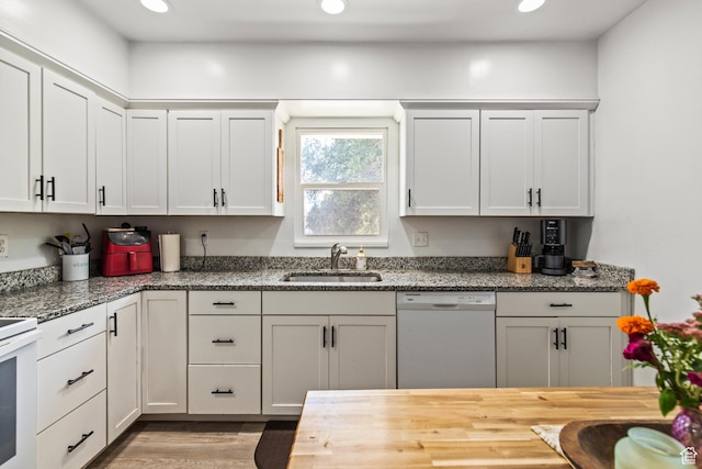 kitchen with a sink, white dishwasher, recessed lighting, and light wood finished floors