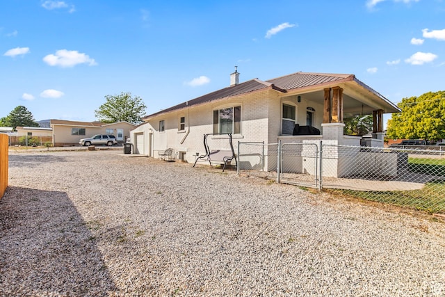 view of side of home with driveway, brick siding, fence, and metal roof