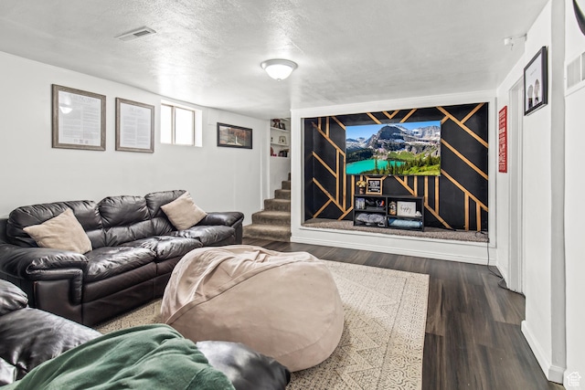 living area with dark wood-style flooring, a textured ceiling, visible vents, and stairs