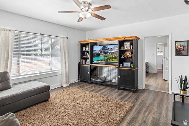 living area featuring baseboards, ceiling fan, and dark wood-style flooring