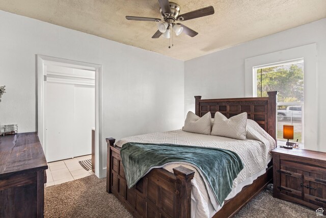 carpeted bedroom featuring tile patterned floors, ceiling fan, and a textured ceiling