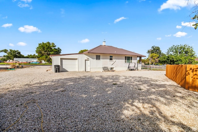 rear view of house with driveway and fence