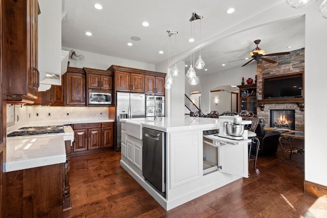10575 S Alexander Park Ln, South Jordan, UT 84095 - kitchen with ceiling fan, a fireplace, arched walkways, light countertops, and stainless steel appliances