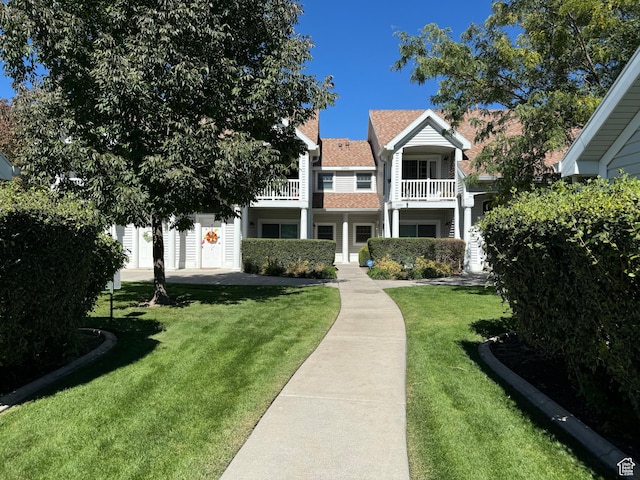 view of front facade featuring a balcony and a front yard