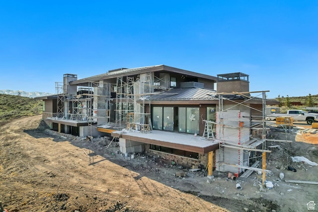 rear view of house with a standing seam roof, a chimney, and metal roof