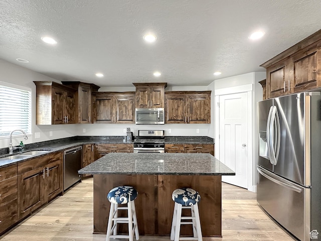 2142 W 3100 S, West Haven, UT 84401 - kitchen with a kitchen bar, a kitchen island, appliances with stainless steel finishes, a sink, and light wood-type flooring