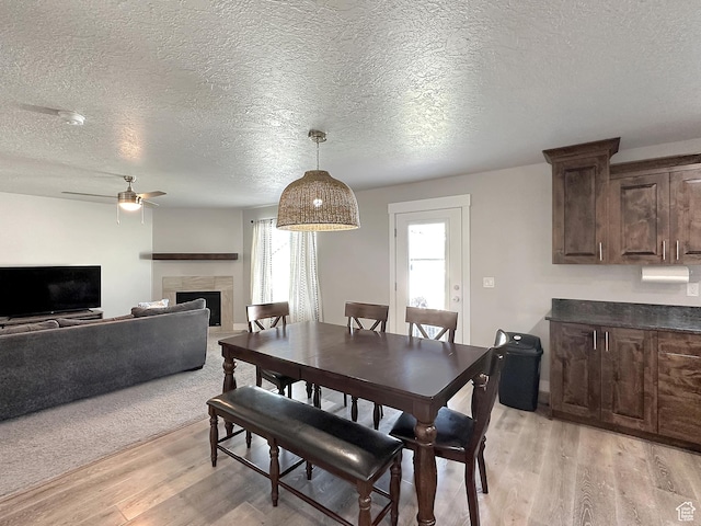 2142 W 3100 S, West Haven, UT 84401 - dining area featuring a fireplace, a textured ceiling, ceiling fan, and light wood-type flooring