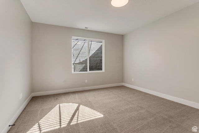 empty room featuring carpet flooring, visible vents, and baseboards