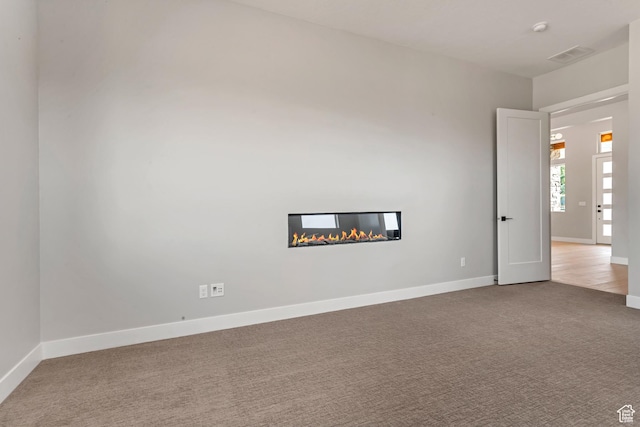 carpeted spare room featuring visible vents and baseboards