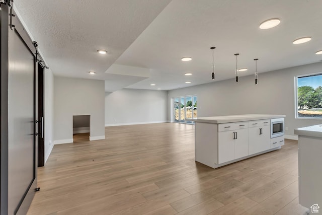 kitchen featuring white cabinets, a barn door, stainless steel microwave, and recessed lighting